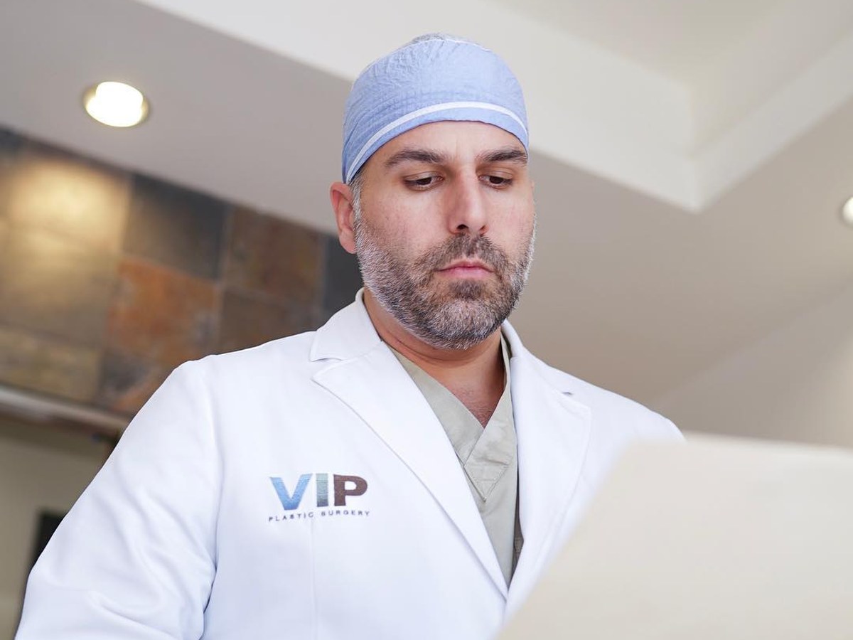 Dr. Khorsandi reviewing a patient chart in scrubs and surgical cap